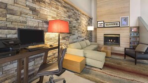 Ein modernes Wohnzimmer mit Steinwand, Kamin, Sofa, Schreibtisch mit Computer und Bücherregal.