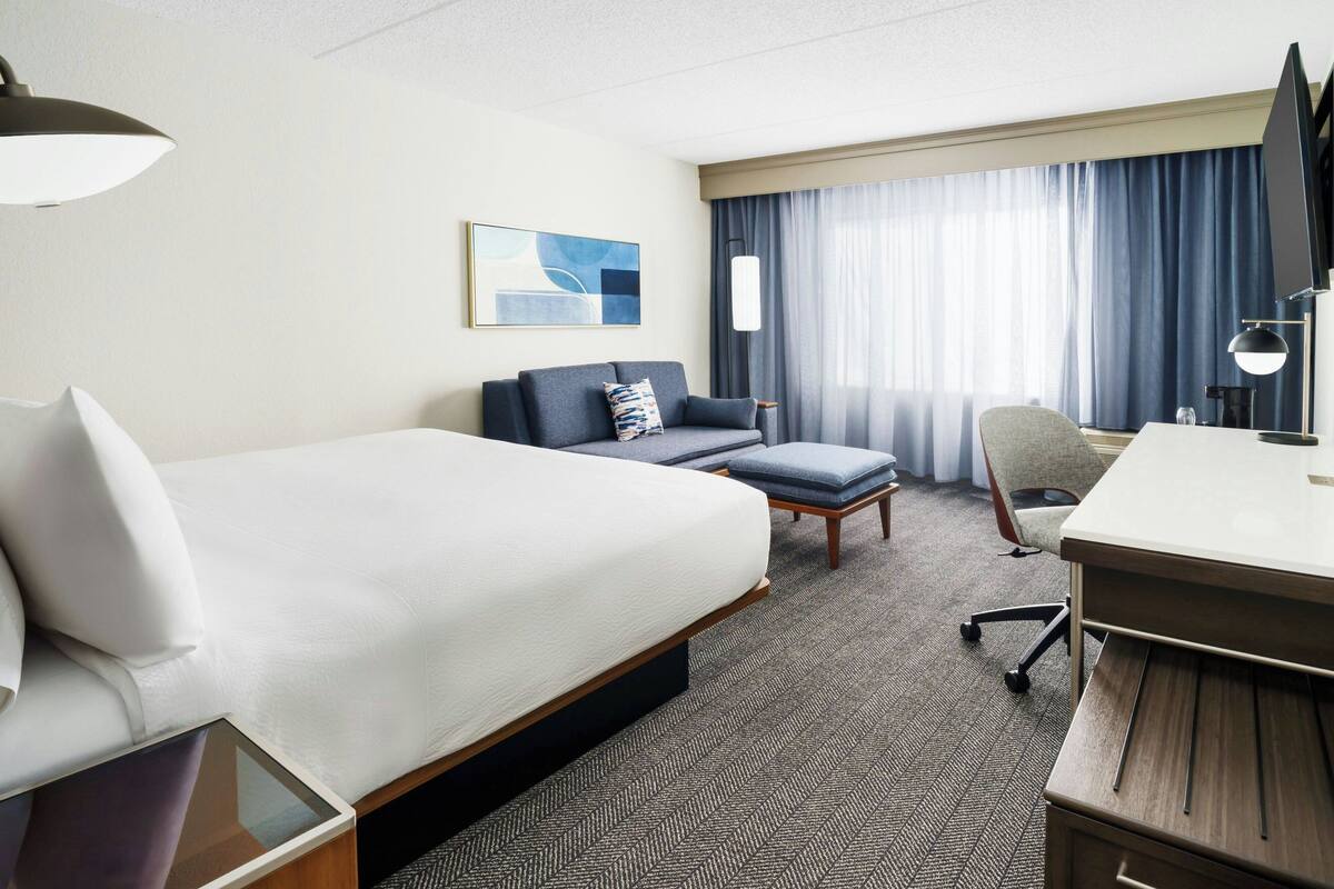 Ein Hotelzimmer mit einem großen Bett, einem Schreibtisch, einem Sessel und einer Couch.