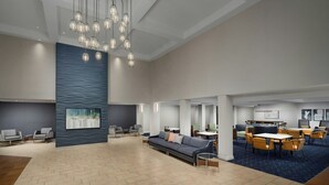 A spacious lobby with a modern chandelier, seating areas, and a large wall-mounted artwork. - Courtyard by Marriott Chicago Midway Airport (Chicago)