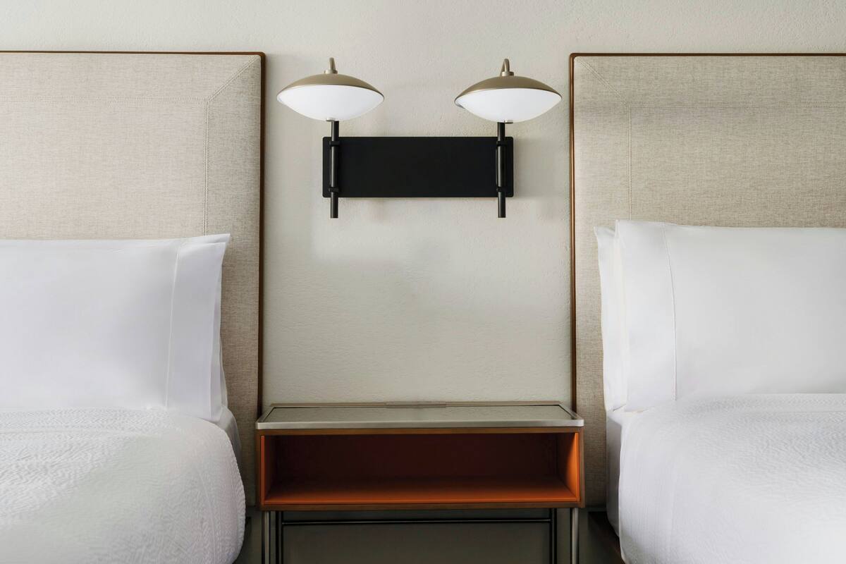 Ein Hotelzimmer mit zwei Betten, einem Nachttisch und einer Wandleuchte.