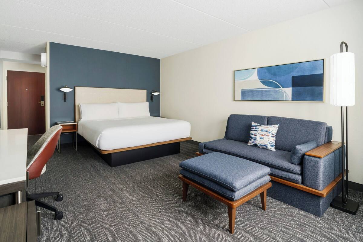 Ein Hotelzimmer mit einem Bett, einem Sofa, einem Schreibtisch und einer Lampe.