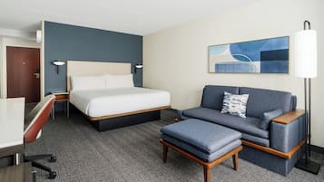 Una habitación de hotel con cama, sofá, escritorio y lámpara.