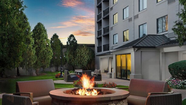 A courtyard with a fire pit, outdoor seating, and a building with a balcony. - Courtyard by Marriott Chicago Midway Airport (Chicago)