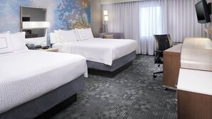 A hotel room with two beds, a desk, a chair, a TV, and a large window with curtains. - Courtyard by Marriott Cleveland Airport North (North Olmsted)