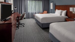 A hotel room with a large bed, a desk with a chair, a television, and a window with curtains. - Courtyard by Marriott New Orleans Covington/Mandeville (Covington)