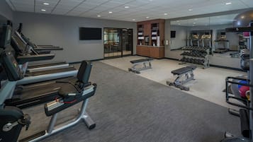 Ein Fitnessstudio mit Laufbändern, Kurzhanteln und Trainingsgeräten.