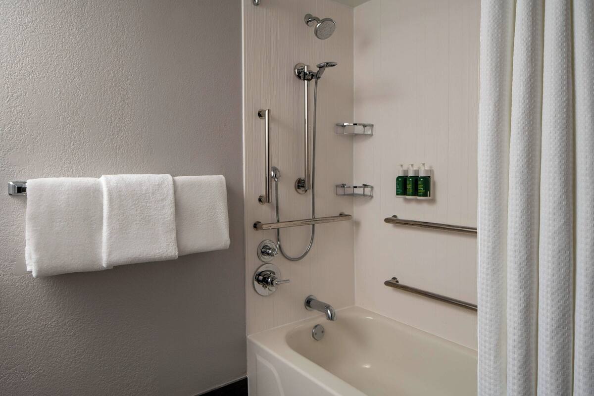 A bathroom with a bathtub, a shower, and a towel rack with three towels.