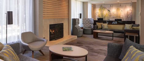 Una sala de estar moderna con chimenea, asientos cómodos y un ventanal con cortinas livianas.