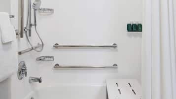 Une salle de bain moderne dotée d’une douche à l’italienne, de barres d’appui, d’une baignoire et d’un porte-serviettes.