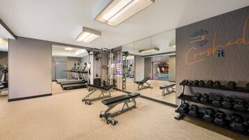 A gym with treadmills, weight machines, and dumbbells.