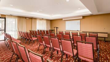 A conference room with rows of chairs, a whiteboard, and a projector screen.