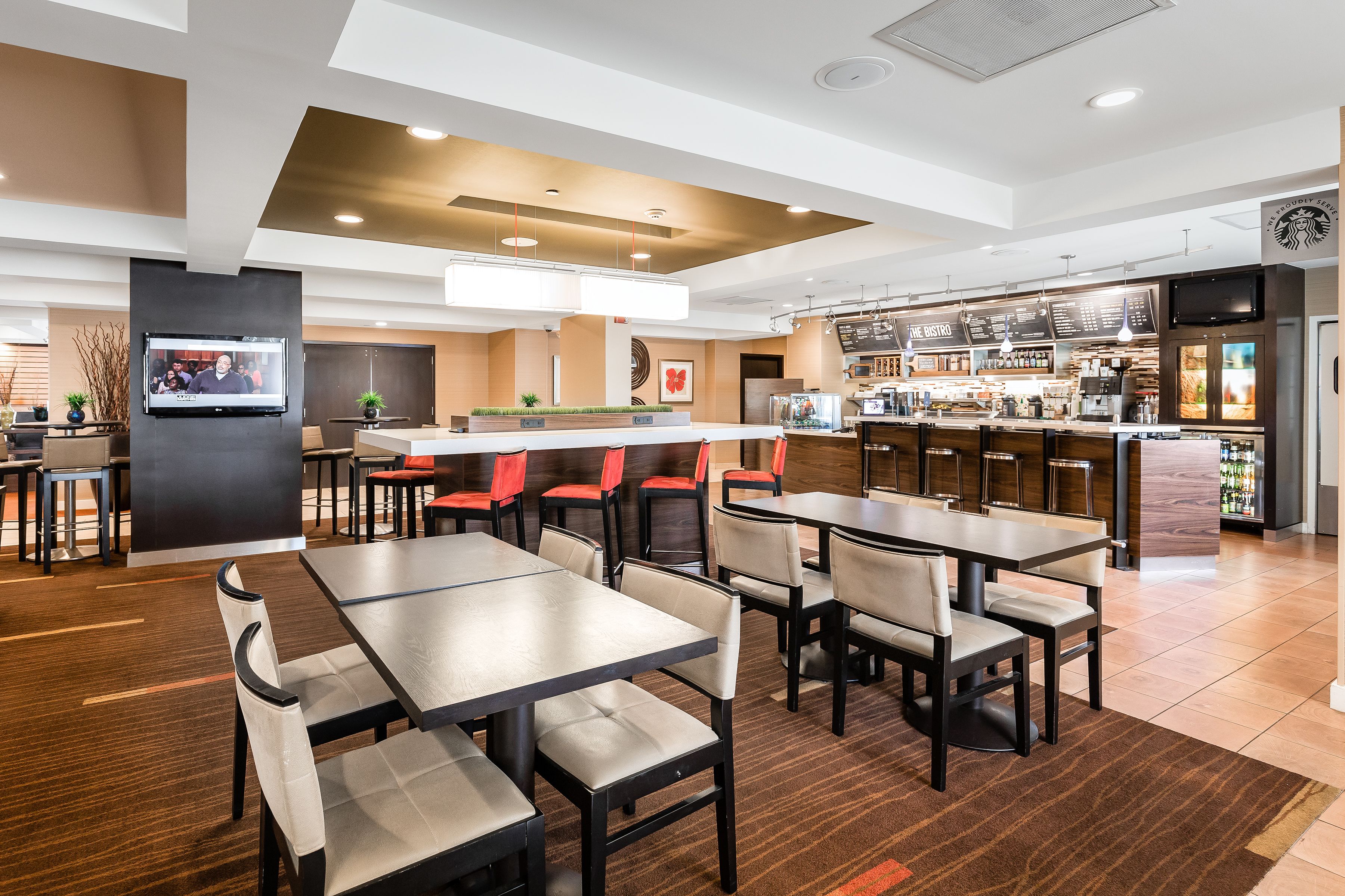 Un restaurante moderno con varias zonas de estar, un bar y una estación de café.