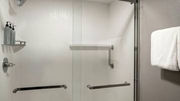 A modern bathroom with a glass shower enclosure, a towel rack, and a shelf with toiletries.