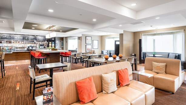 A modern hotel lobby with a dining area, seating arrangements, and a bar. - Courtyard by Marriott Gulf Shores Craft Farms (Gulf Shores)