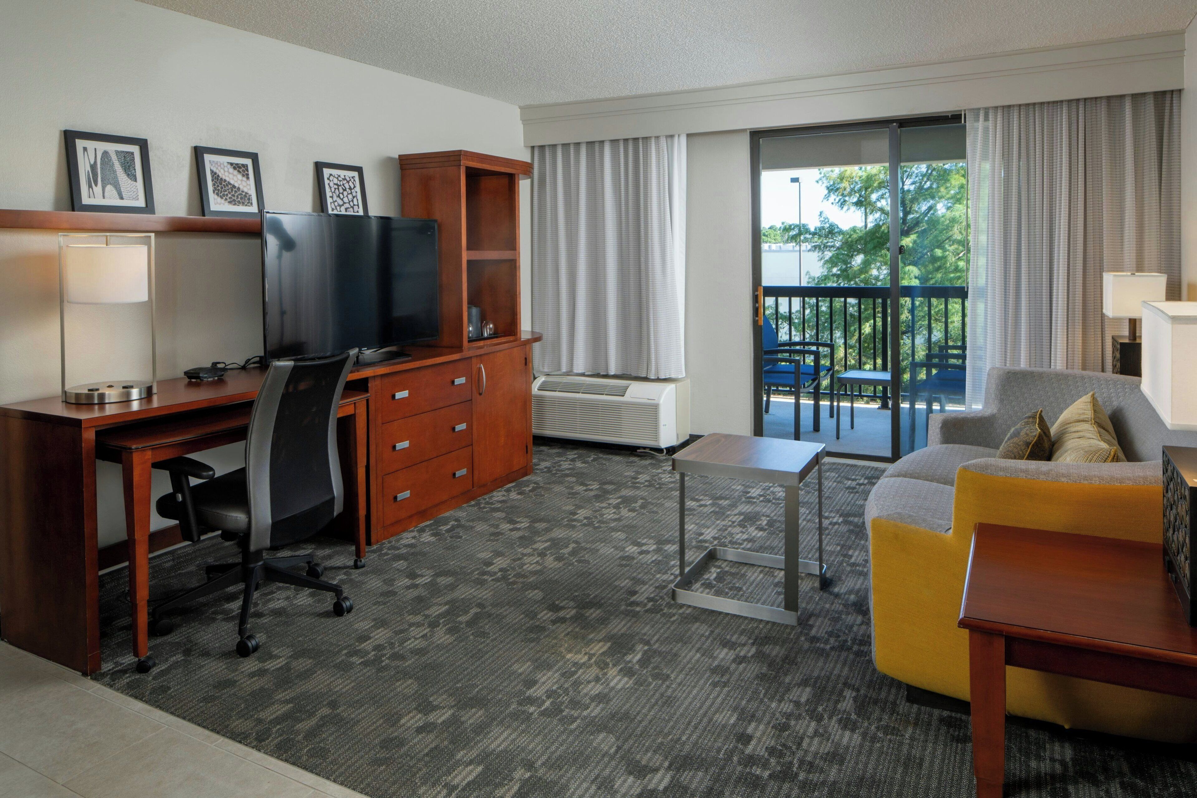 Una habitación de hotel con escritorio, silla, televisor y sofá.