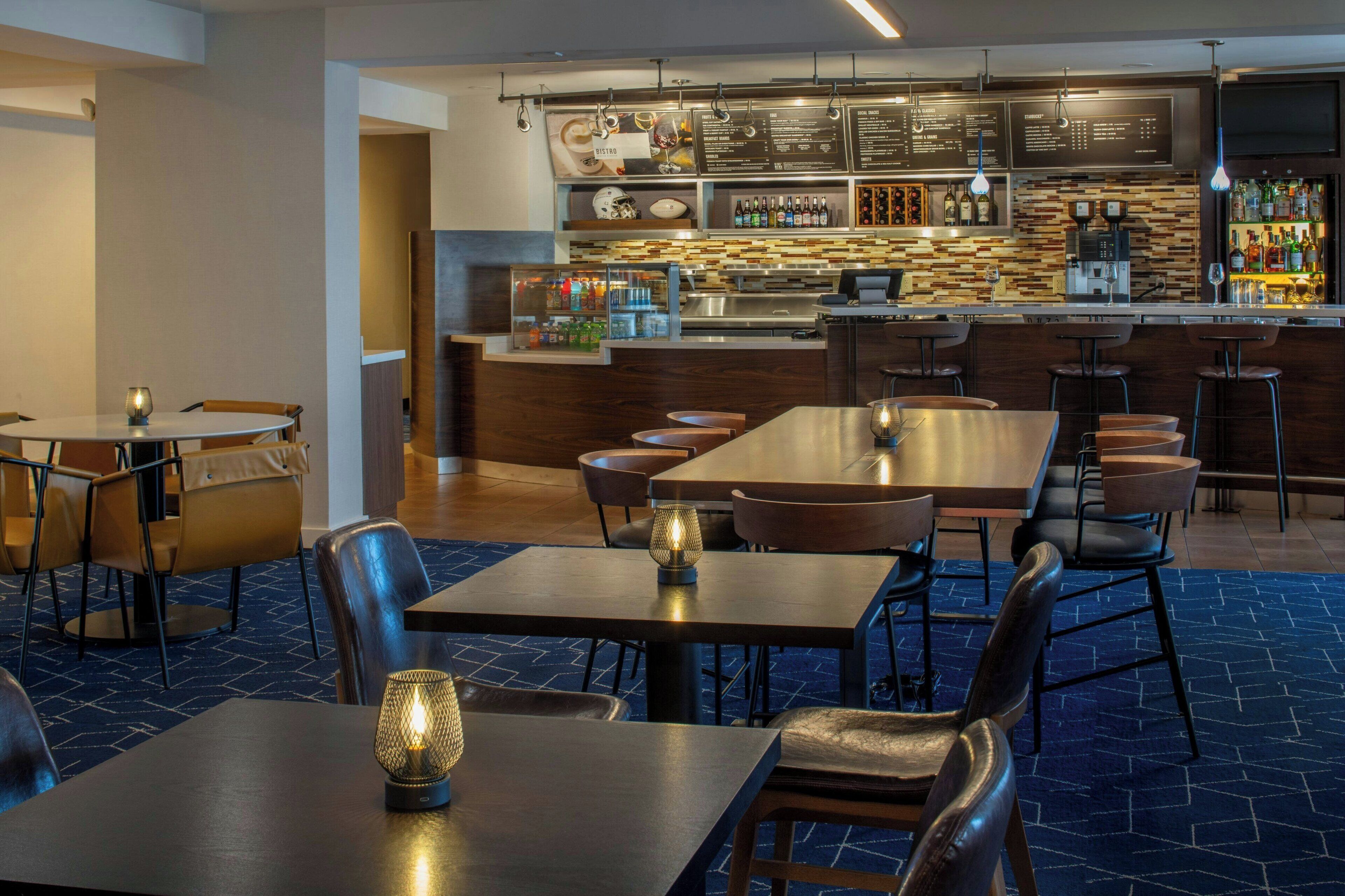 Un restaurante moderno con una zona de bar, diversas opciones de asientos y una variedad de bebidas a la vista.