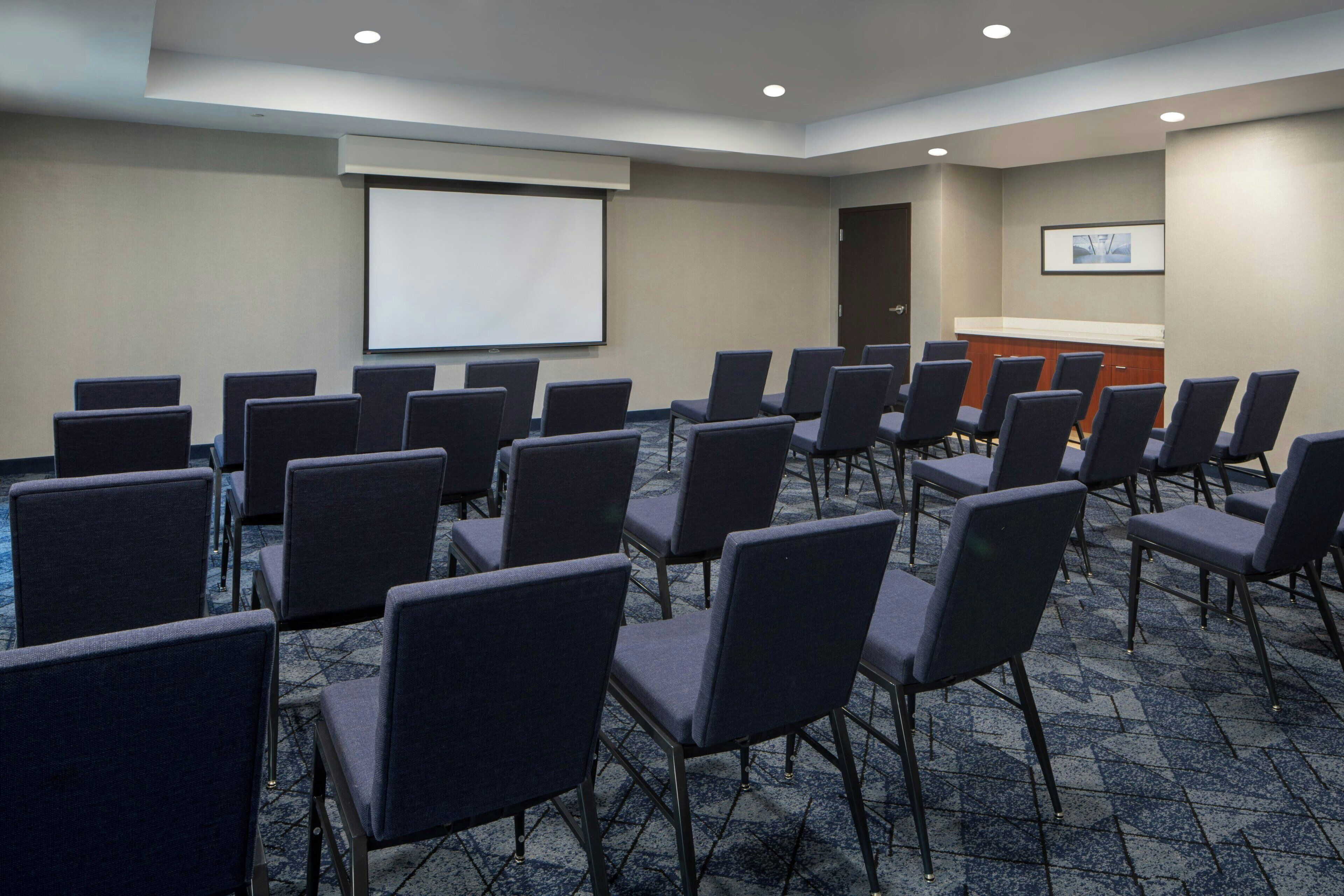 A conference room with rows of chairs, a projector screen, and a podium.