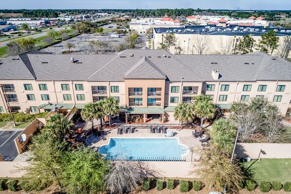 A hotel with a swimming pool, multiple balconies, and a landscaped courtyard.