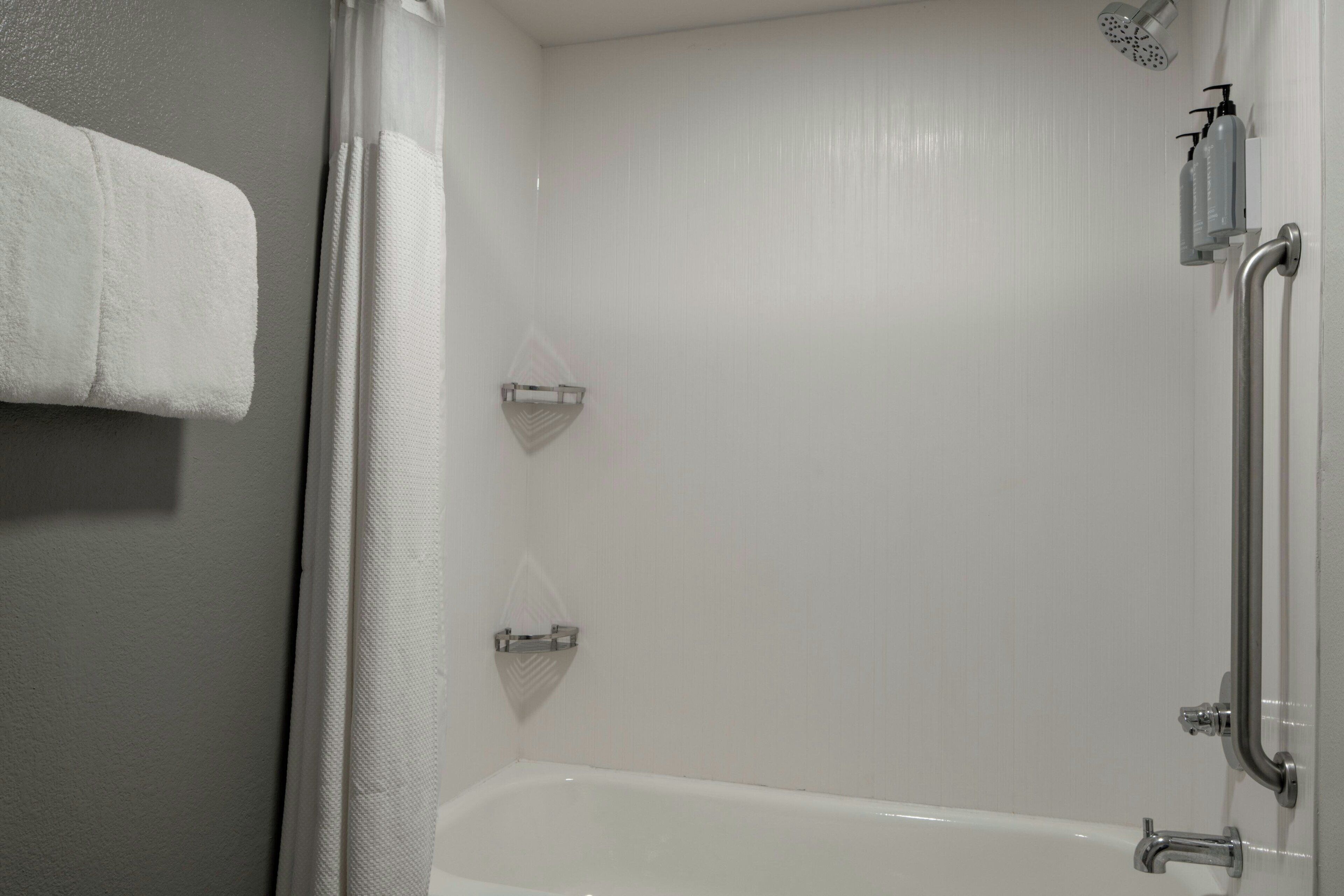 A bathroom with a white bathtub, a shower area, and a towel rack.