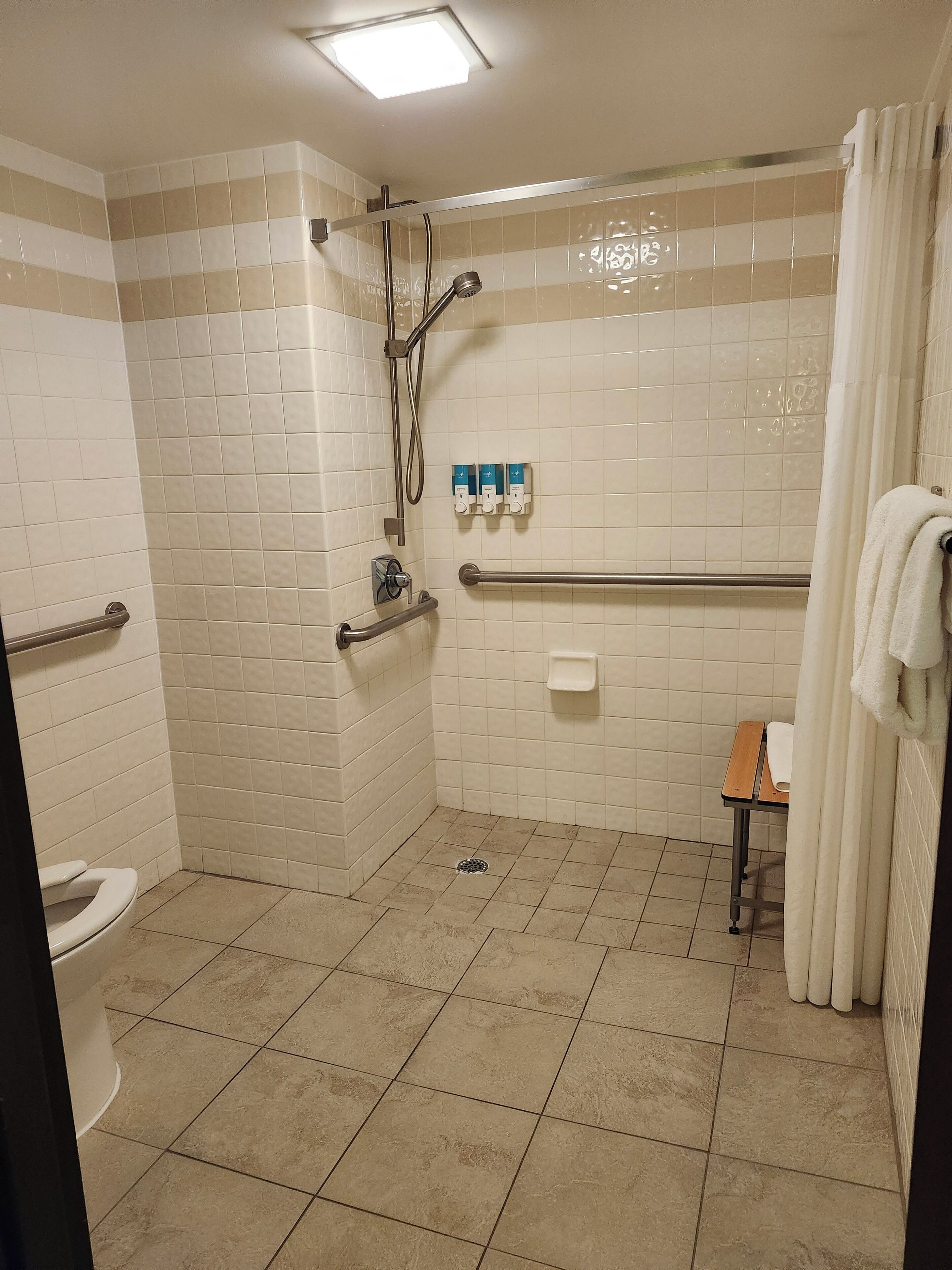 Ein Badezimmer mit Dusche, Toilette und einem kleinen Tisch mit einem Handtuch.