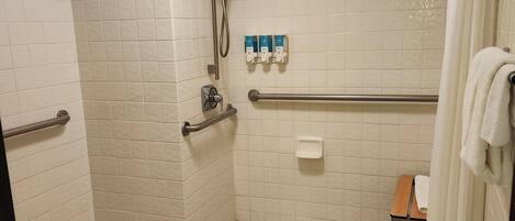 Ein Badezimmer mit Dusche, Toilette und einem kleinen Tisch mit einem Handtuch.