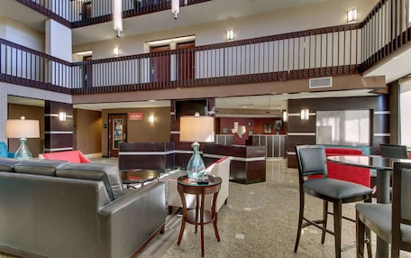 A hotel lobby with a seating area, a reception desk, and a staircase.
