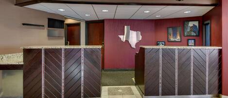 A reception area with two counters, a red wall with a Texas state outline, and framed pictures.