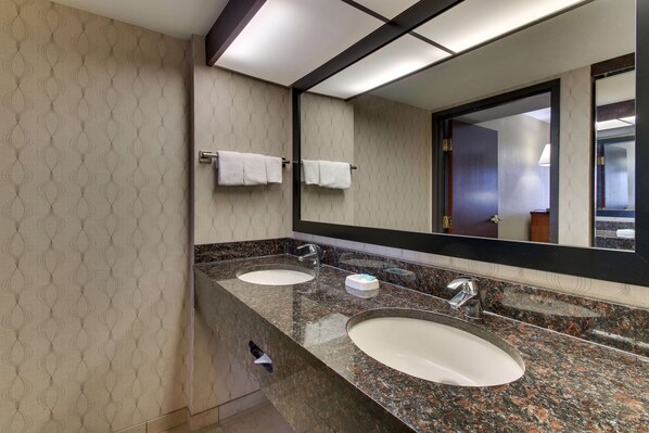 A modern bathroom with two sinks, a large mirror, and a towel rack.