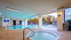 Un espace piscine comprenant un jacuzzi, une signalisation claire et une vue sur l’extérieur.