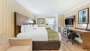 Een hotelkamer met een groot bed, een bureau, een stoel, een televisie en een schilderij aan de muur.