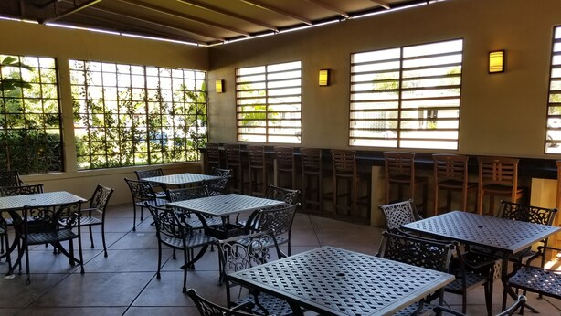 An indoor dining area with tables and chairs, large windows with blinds, and a ceiling with fluorescent lighting. - Quality Inn & Suites Anaheim Maingate (Anaheim)
