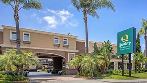 Een hotel met een bord waarop staat 'Quality Inn & Suites by Choice Hotels' en een parkeerplaats met meerdere auto's.