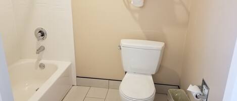 Et badeværelse med et hvidt badekar, toilet og en skraldespand.
