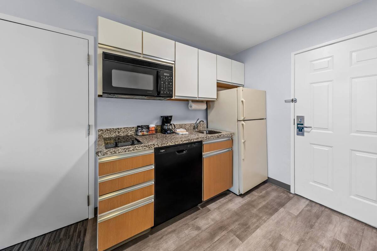 A kitchen with white cabinets, a microwave, a dishwasher, a refrigerator, and a sink.