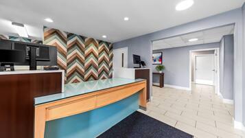Zona de recepción con un mostrador moderno, un espejo grande y una pared con diseño en chevron.