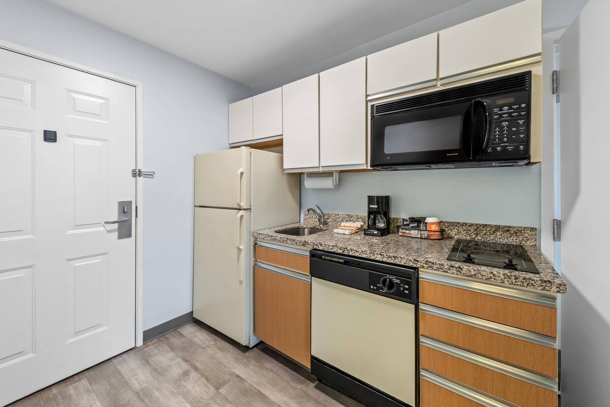 A compact kitchen with a refrigerator, microwave, coffee maker, and dishwasher.