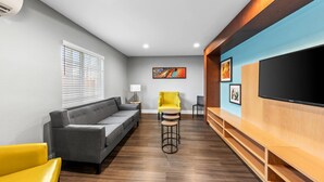 A modern living room with a sofa, a yellow chair, a TV, and artwork on the wall. - MainStay Suites Cincinnati Blue Ash (Cincinnati)