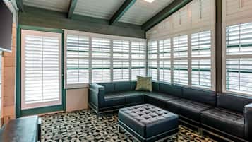 A modern waiting area with a sectional sofa, a tufted ottoman, and a patterned floor.