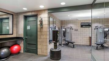 Une salle de sport équipée de matériel d’exercice, d’un sac de frappe et d’un miroir.