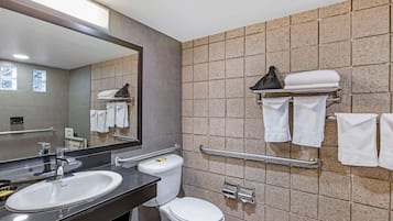 Uma casa de banho moderna com lavatório, sanita e barras de apoio.
