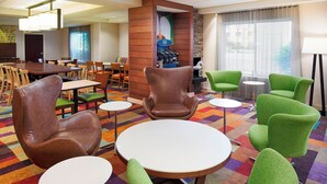 Eine Hotelhalle mit einem großen Esstisch, mehreren Stühlen, einem kleinen Couchtisch und einem Kamin.