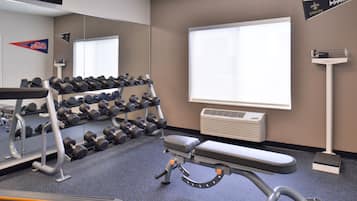 A gym with a bench, dumbbells, and a treadmill.