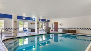 Una piscina interior amb aigua blava cristal·lina, una zona de solàrium amb rajoles i unes quantes gandules.