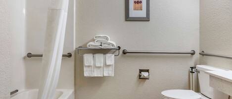 A bathroom with a bathtub, toilet, and a towel rack with folded towels.