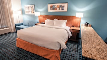 Ein Hotelzimmer mit einem großen Bett, einem blau gemusterten Teppich, zwei Wandlampen und einem gerahmten Bild über dem Bett.