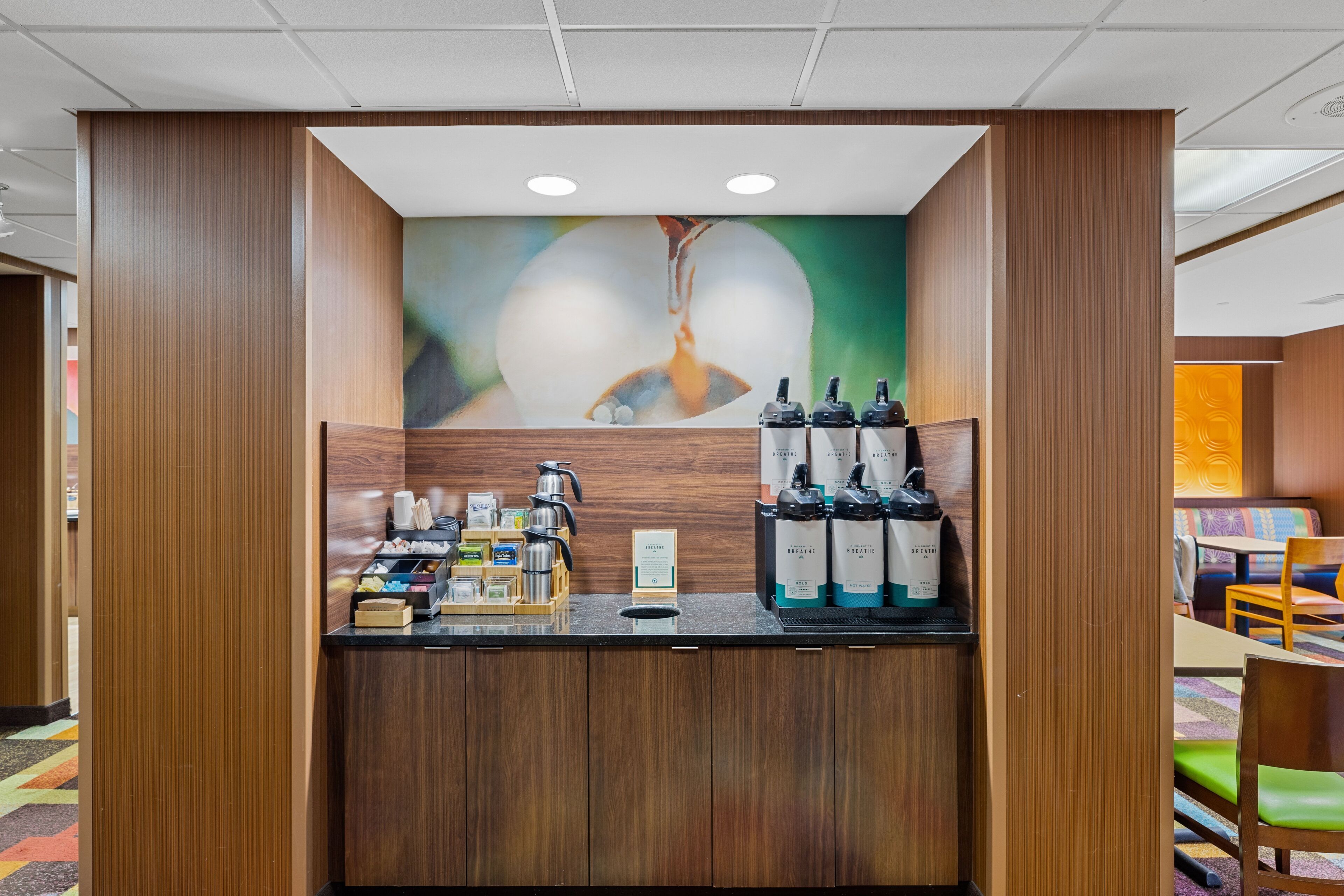 A reception area with a wooden counter, coffee machines, and bottled water.
