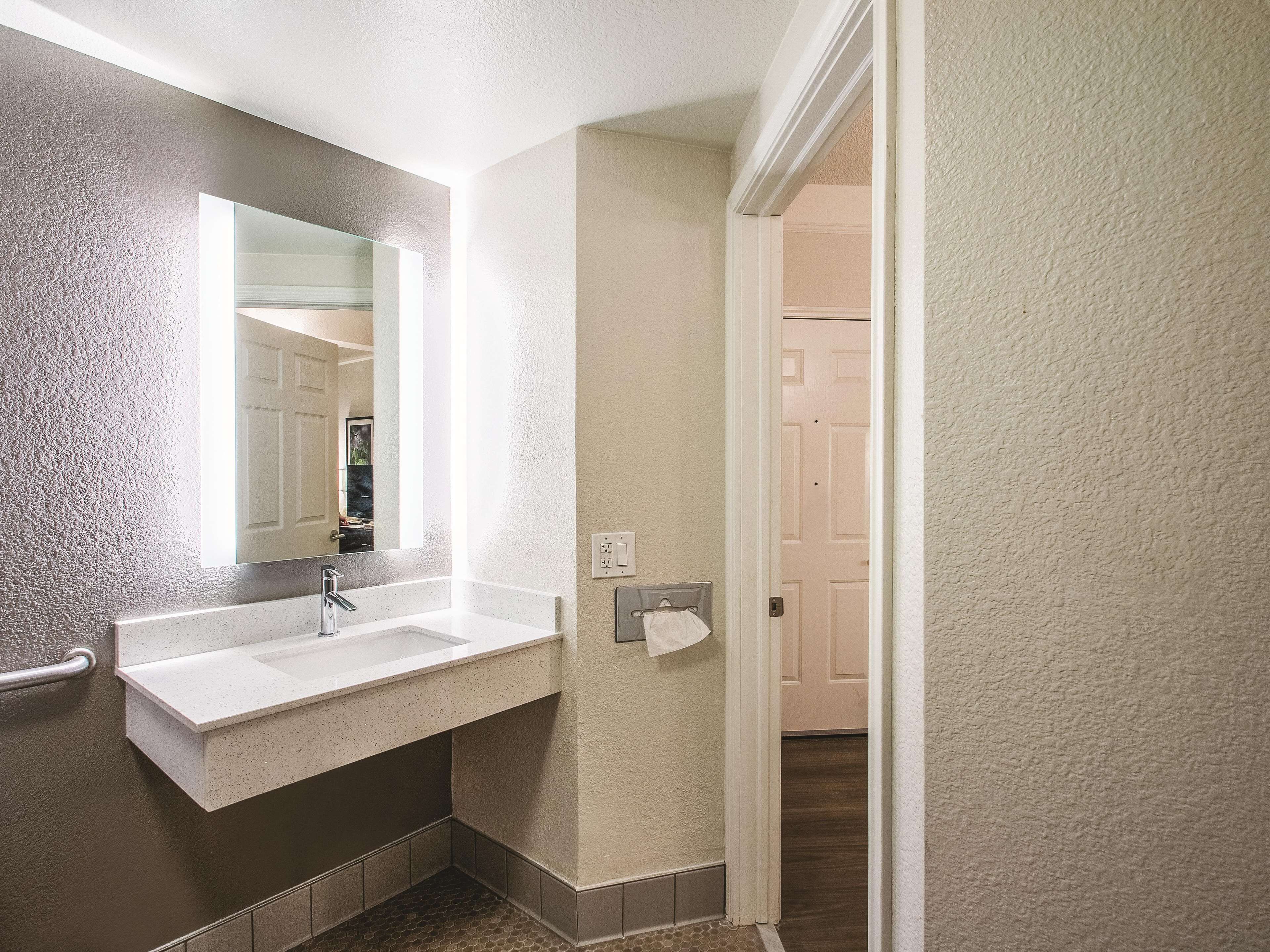 A bathroom with a white sink, a mirror, and a towel rack.