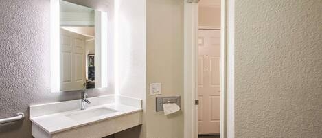 A bathroom with a white sink, a mirror, and a towel rack.