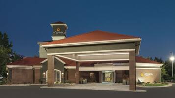 A hotel with a covered entrance, a red roof, and a sign reading "La Quinta".