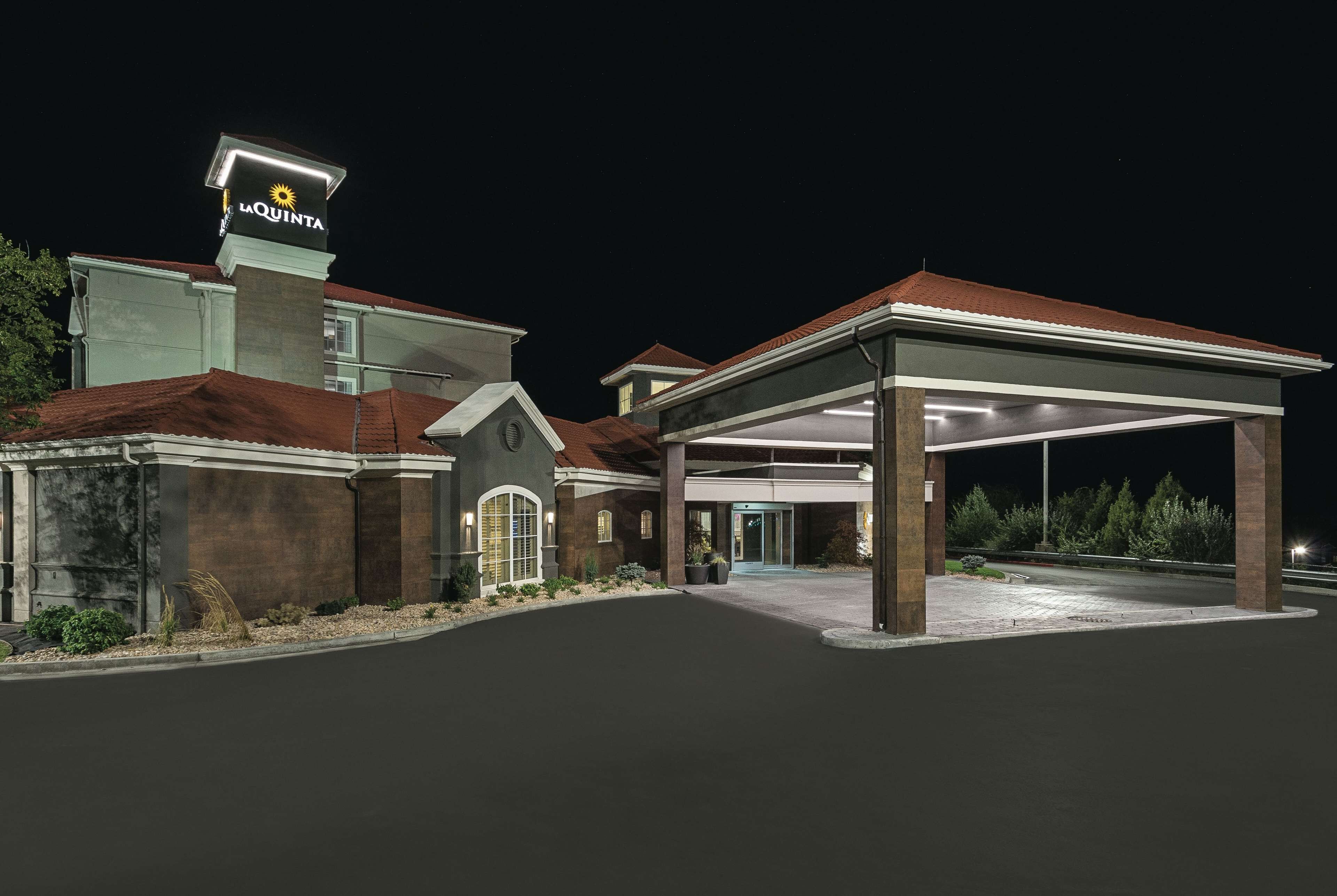 A hotel with a prominent sign, a covered entrance, and a well-lit driveway.